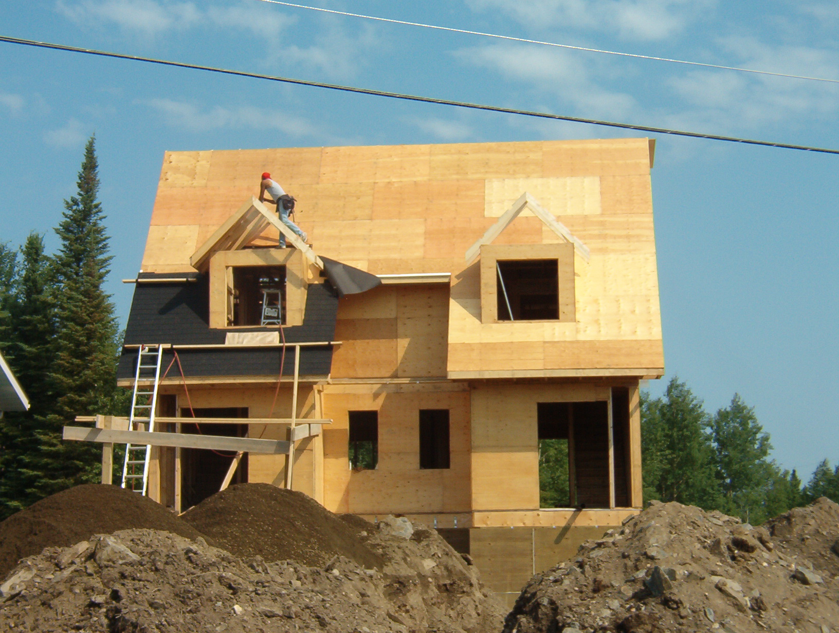 A worker on the building, as they start to put the shingles on the roof.