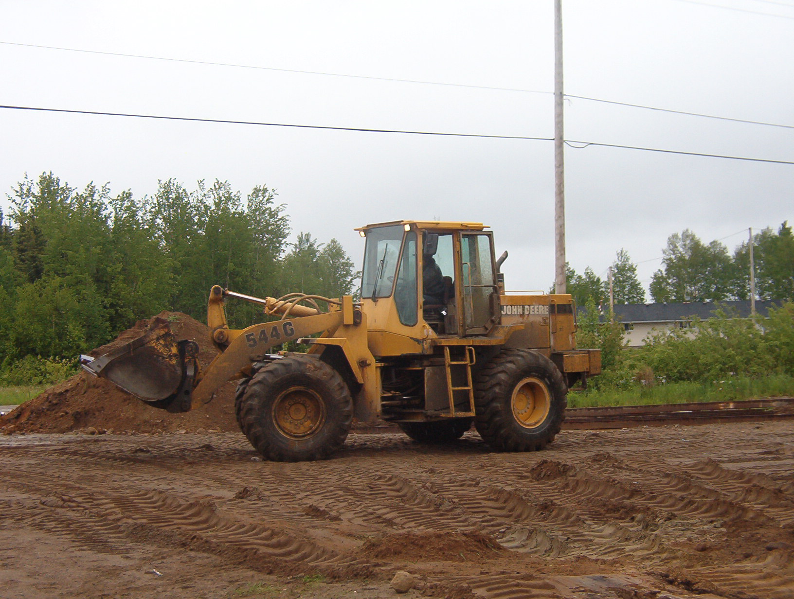 The tractor, that Gary, is driving to help clear the gravel around the building.