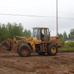 The tractor, that Gary, is driving to help clear the gravel around the building.