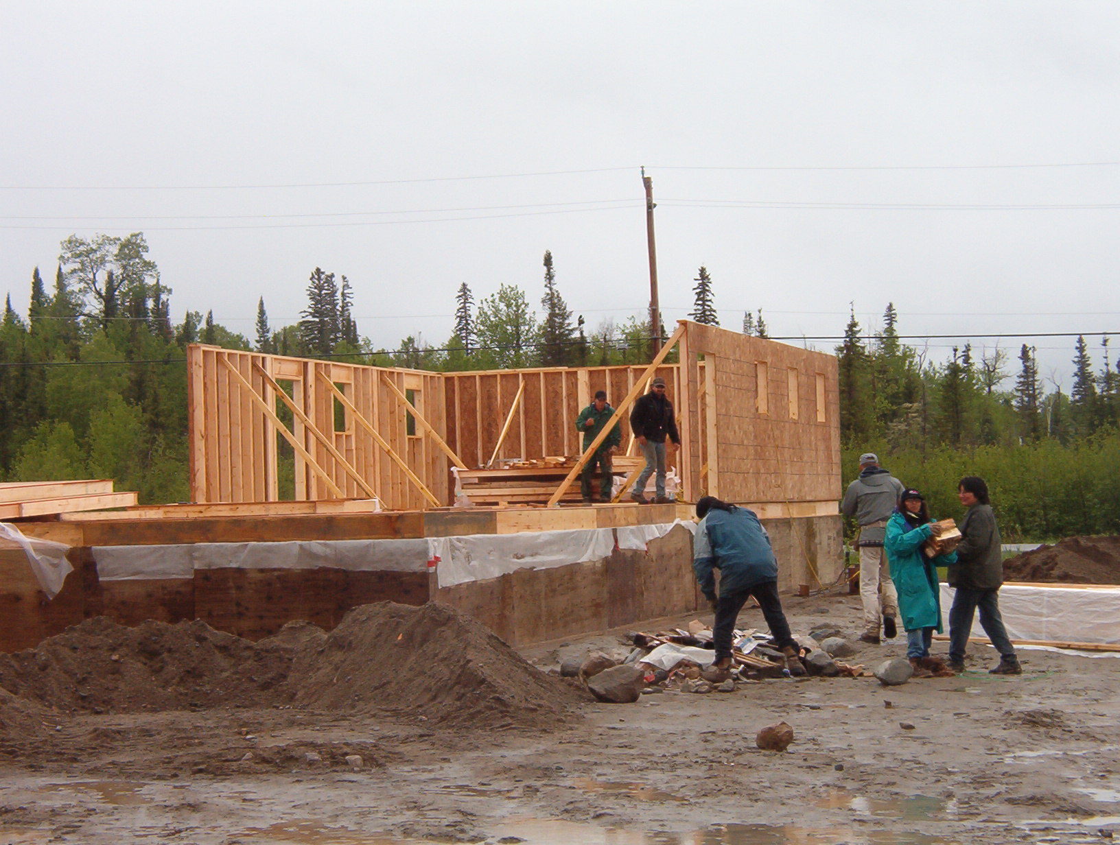 Part of the walls going up, as the other workers, start cleaning around the area.