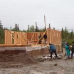 Part of the walls going up, as the other workers, start cleaning around the area.