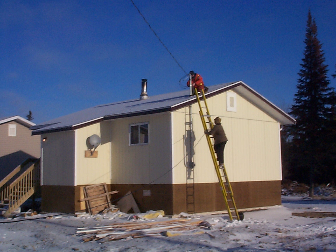 Climbing on top the roof to place the wiring for internet access to the homes in North Spirit Lake.